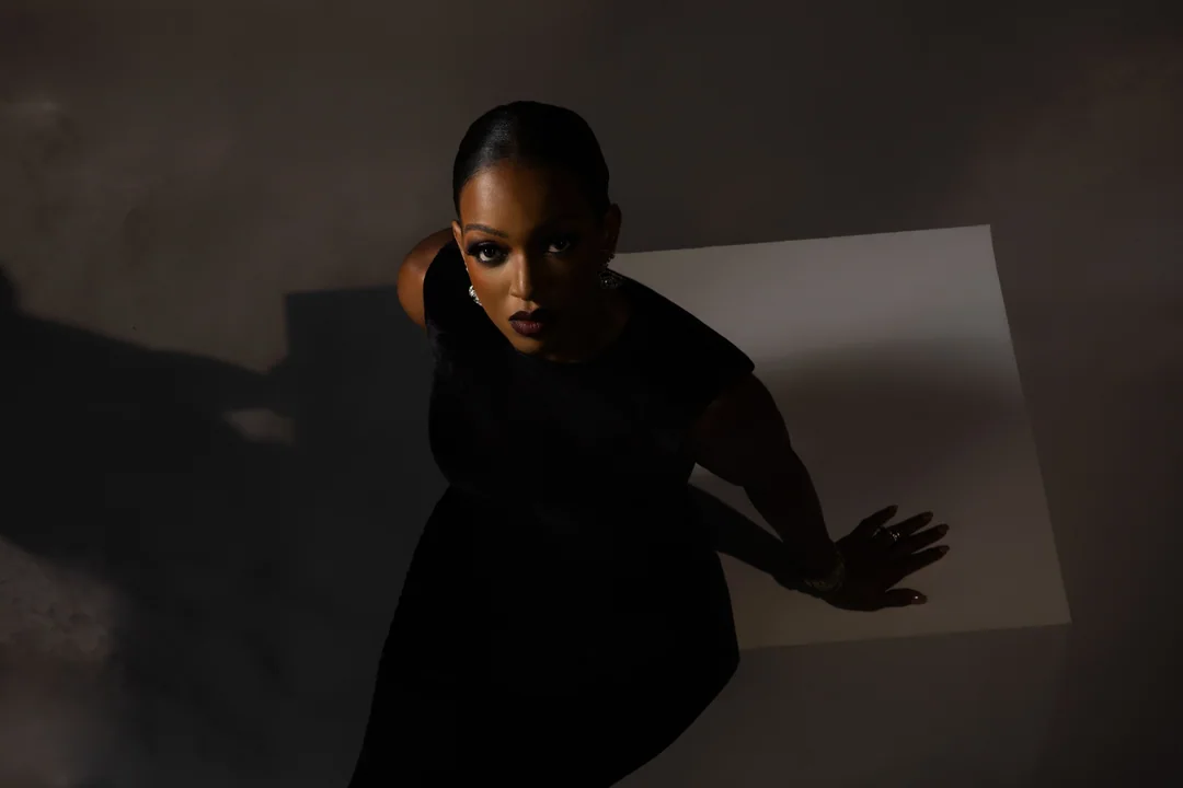 Woman in black crouched in dramatic low light
