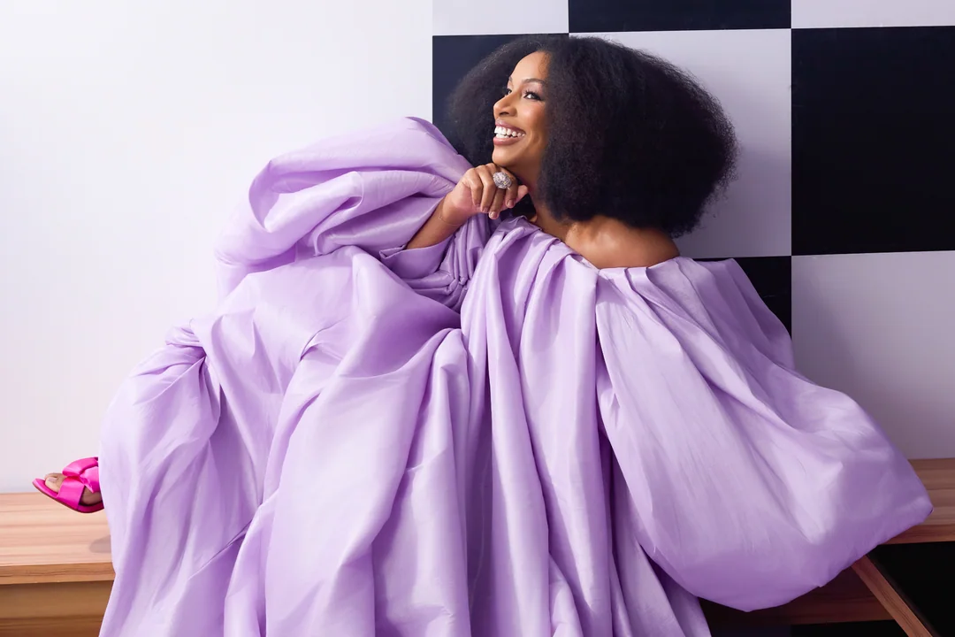 Woman in a voluminous lilac gown before a checkerboard wall