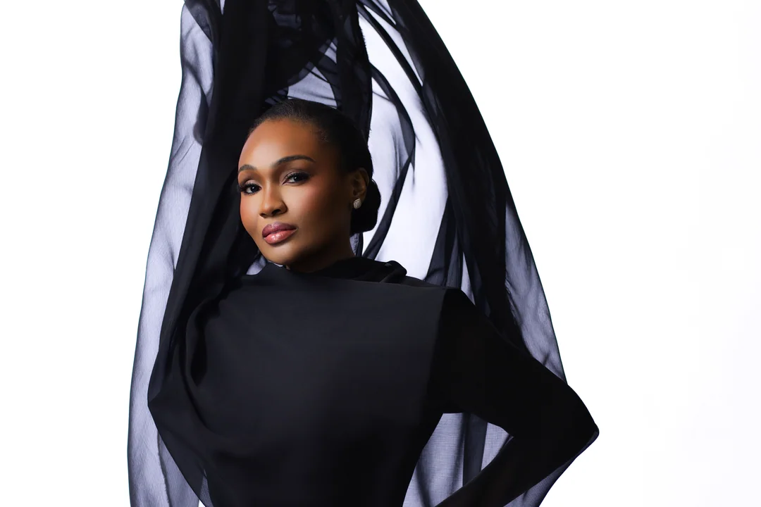 Woman wrapped in sheer black fabric against a white wall