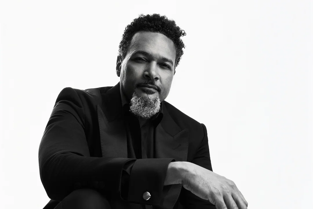 Black-and-white portrait of a bearded man seated in a dark suit